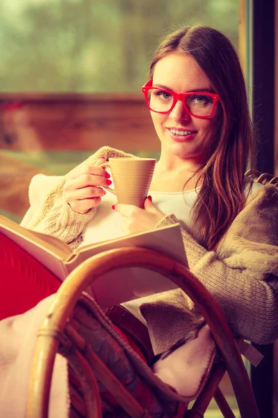Vrouw zit op stoel het lezen van boek thuis — Stockfoto