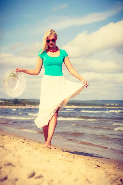 Mujer rubia usando vestido caminando en la playa — Foto de Stock