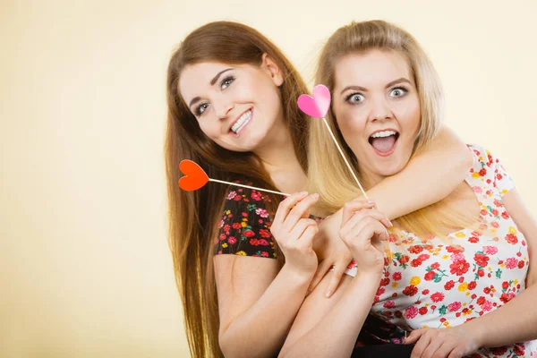 Duas mulheres felizes segurando o coração no pau — Fotografia de Stock