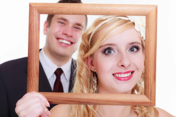 Groom and bride holding empty frame — Stock Photo, Image