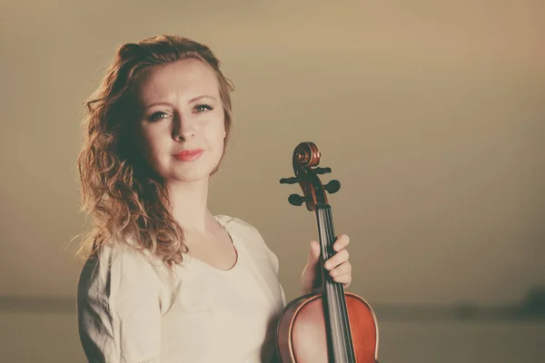 Woman on beach near sea holding violin — Stock Photo, Image