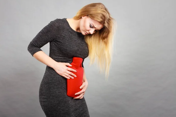 Menina com dor de estômago, segurando garrafa de água quente — Fotografia de Stock