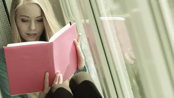 Mujer leyendo en alféizar de ventana — Foto de Stock