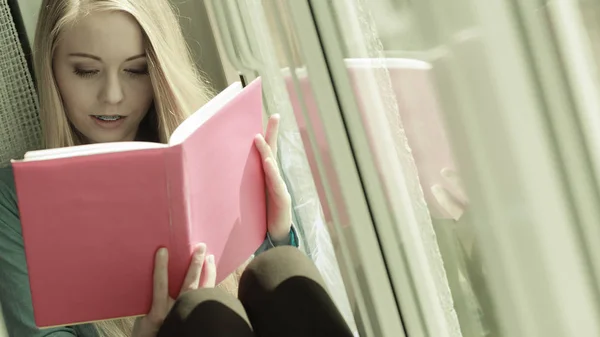 Woman reading on windowsill — Stock Photo, Image