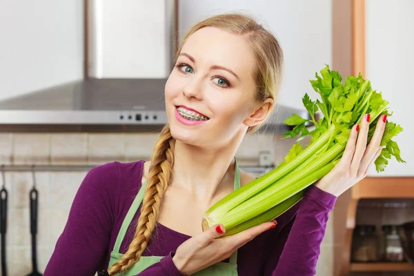 Femme dans la cuisine tient céleri vert — Photo