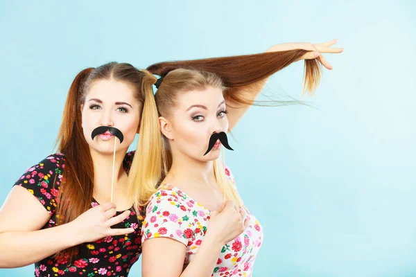 Twee gelukkige vrouwen houden van valse snor op stick — Stockfoto