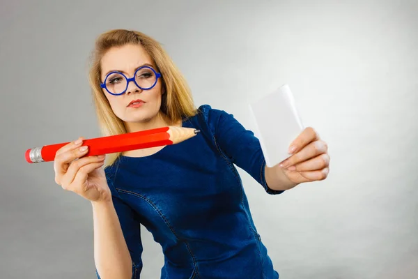Ernstige vrouw houdt grote potlood nota papier in de hand — Stockfoto