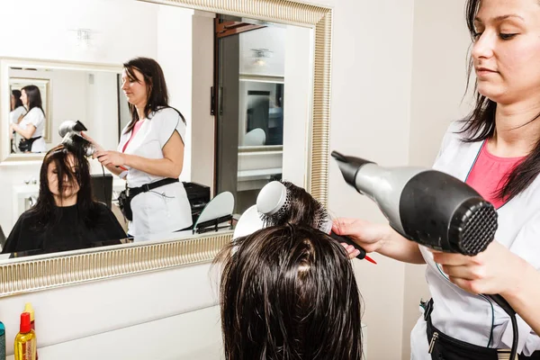 Kadeřník sušení tmavě ženské vlasy pomocí profesionální fén — Stock fotografie
