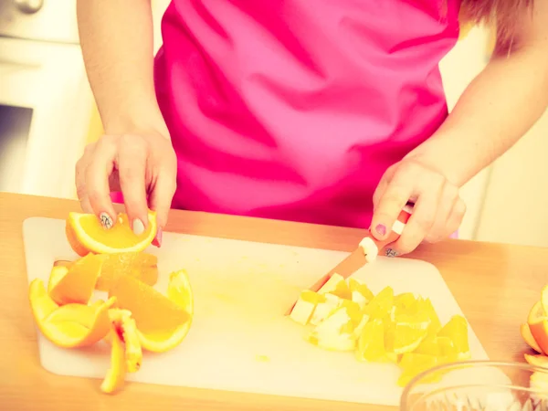 Kvinnan hemmafru i köket skär orange frukter — Stockfoto