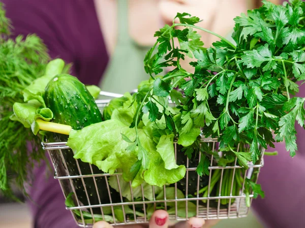 Mulher na cozinha com legumes segurando cesta de compras — Fotografia de Stock