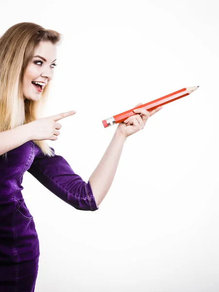 Smiling woman holds big pencil in hand — Stock Photo, Image