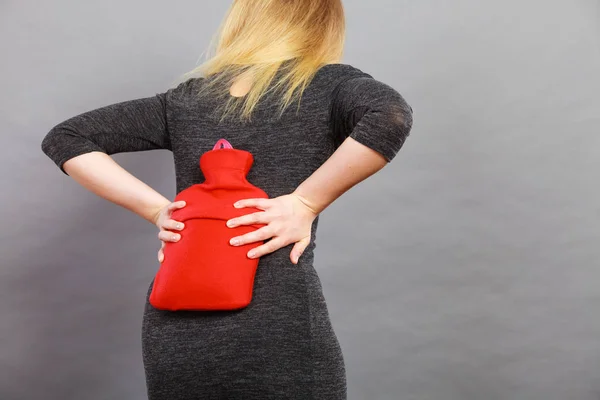 Girl having back pain, holding hot water bottle — Stock Photo, Image