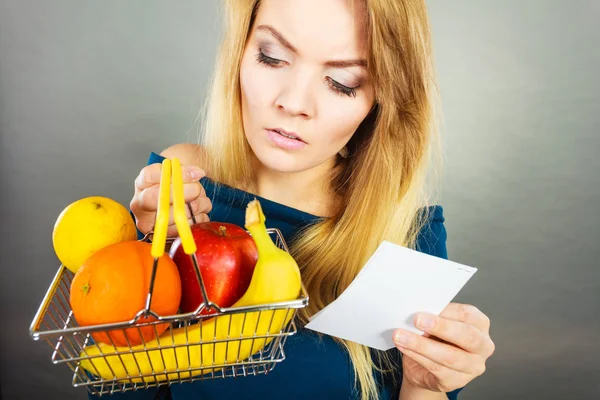 Mulher preocupada segurando cesta de compras com frutas — Fotografia de Stock