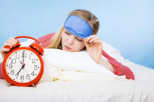 Śpiąca kobieta piżamie gospodarstwa zegar — Zdjęcie stockowe