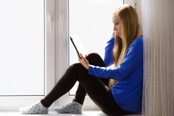 Estudiante chica con la tableta sentado en el alféizar de la ventana —  Fotos de Stock