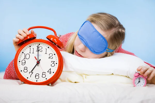 Sleeping woman wearing pajamas holding clock — Stock Photo, Image