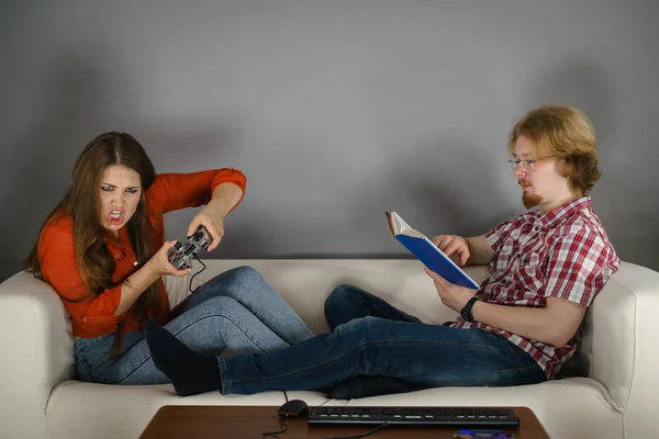 Woman playing games man reading book — Stock Photo, Image