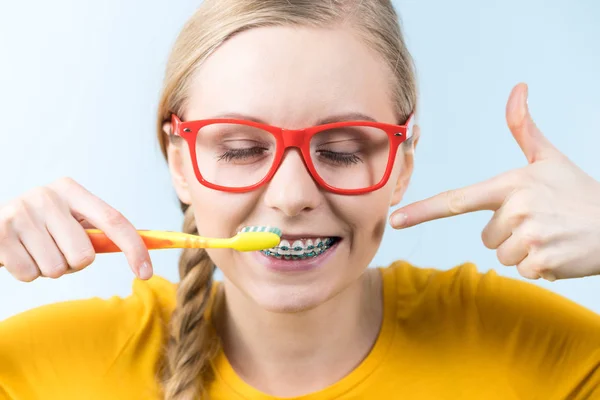 Woman smiling cleaning teeth with braces — Stock Photo, Image