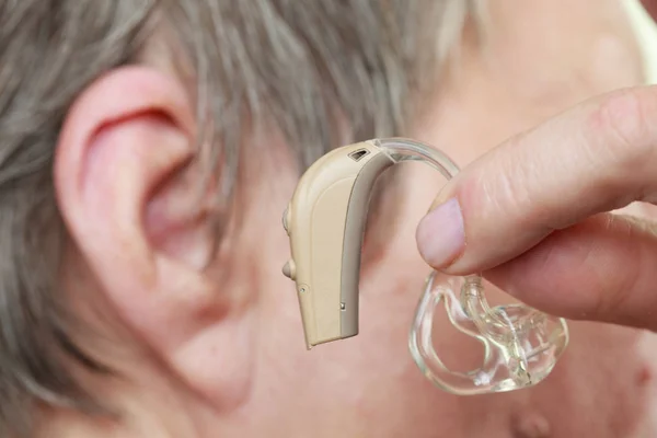 Closeup senior woman using hearing aid — Stock Photo, Image