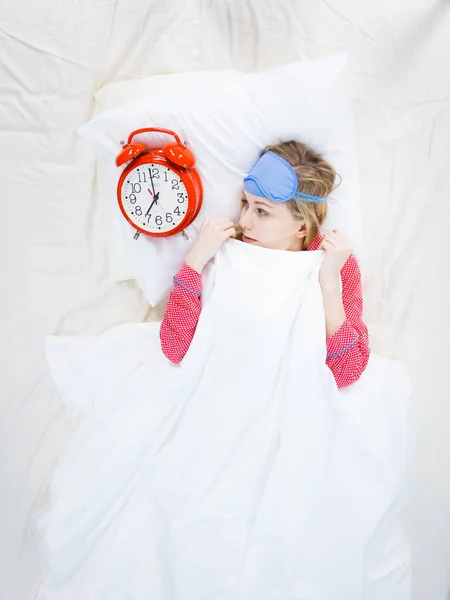 Mujer somnolienta usando pijamas sosteniendo reloj —  Fotos de Stock