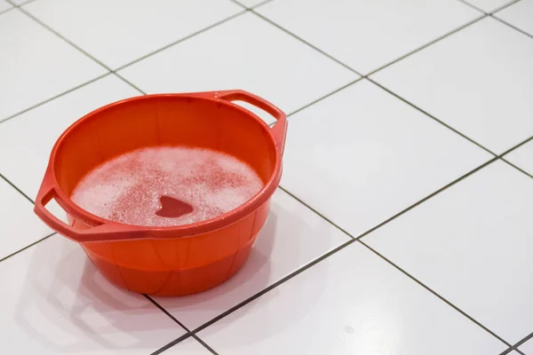 Rote Schüssel gefüllt mit Spülmittel und Wasser — Stockfoto