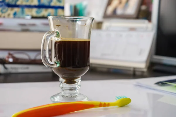 Schwarzer dunkler Espresso-Kaffee und Zahnbürste auf dem Tisch — Stockfoto