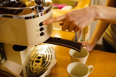 Woman making hot drink in coffee machine clipart