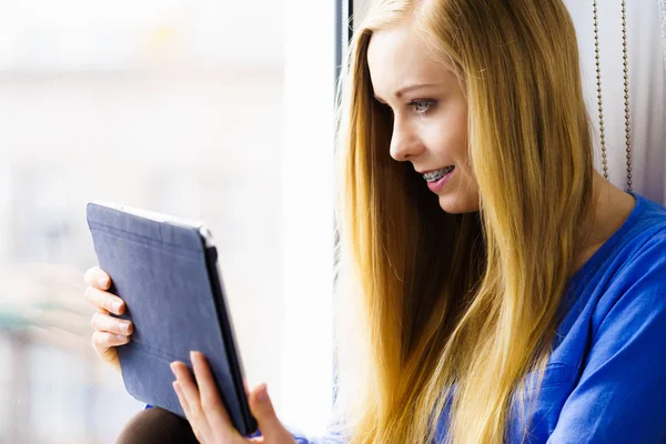 Estudiante chica con la tableta sentado en el alféizar de la ventana — Foto de Stock