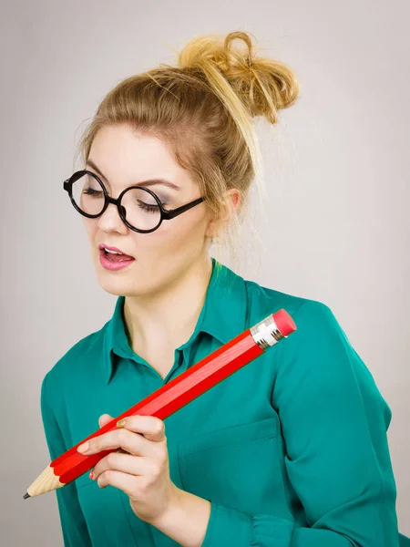Smiling woman holds big pencil in hand — Stock Photo, Image