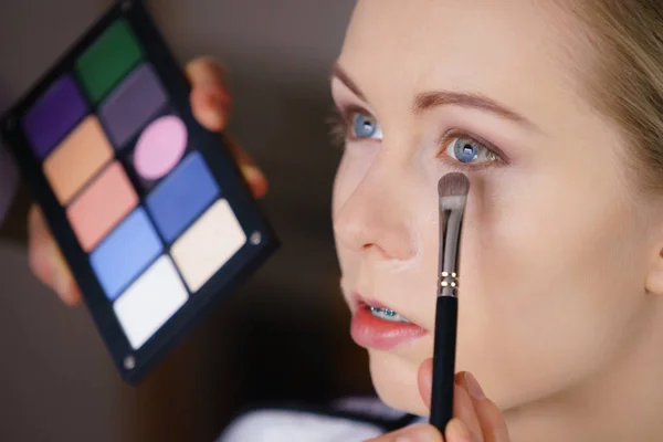 Vrouw krijgt make-up gedaan door kunstenaar — Stockfoto