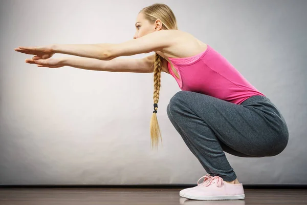 Mujer entrenando en casa haciendo sentadillas — Foto de Stock