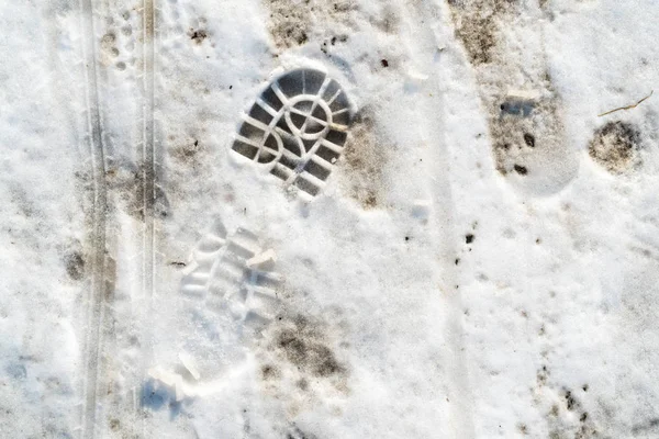 Derretimiento de nieve con huellas de zapatos humanos — Foto de Stock