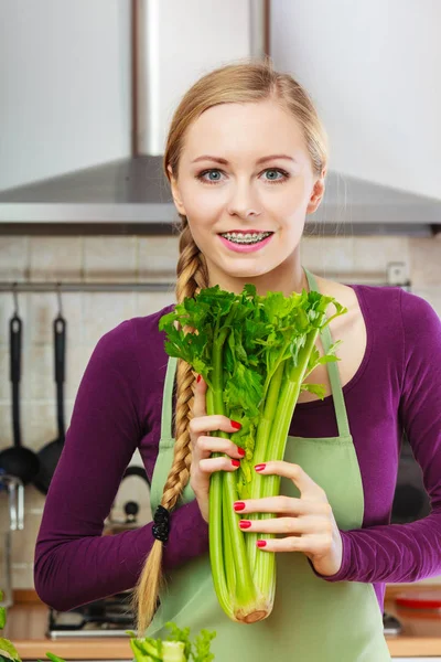 Donna in cucina tiene sedano verde — Foto Stock