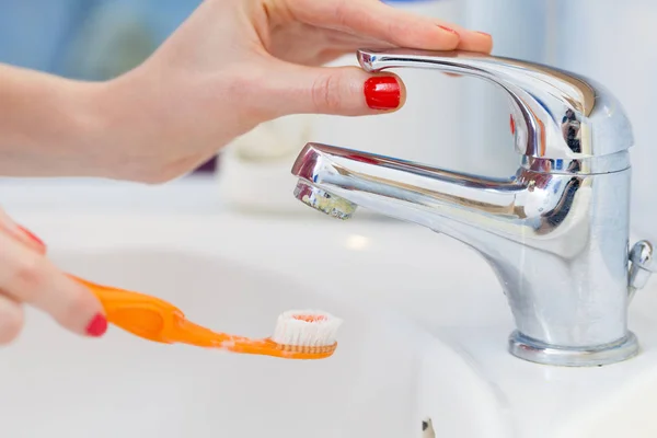 Woman cleaning her toothbrush — Stock Photo, Image