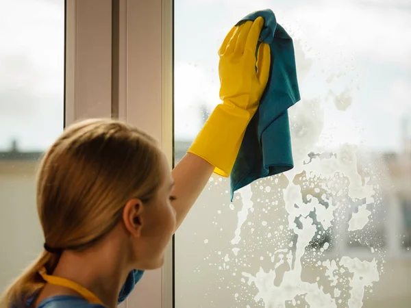 Девушка моет окно дома тряпкой для стирального порошка — стоковое фото