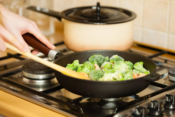 Женщина готовит перемешать жарить замороженные овощи на сковороде — стоковое фото