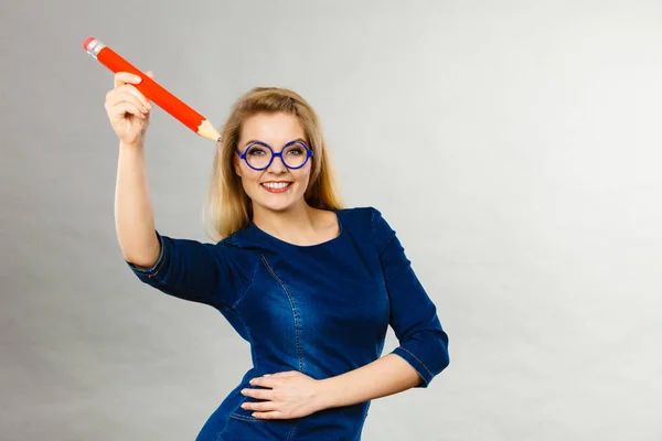 Mujer sonriente sostiene un lápiz grande en la mano — Foto de Stock