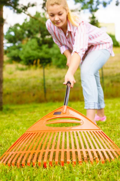 Mulher usando ancinho para limpar o jardim — Fotografia de Stock