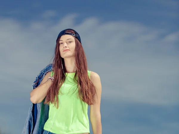 Teenager girl in cap listening to music outdoor. — Stock Photo, Image