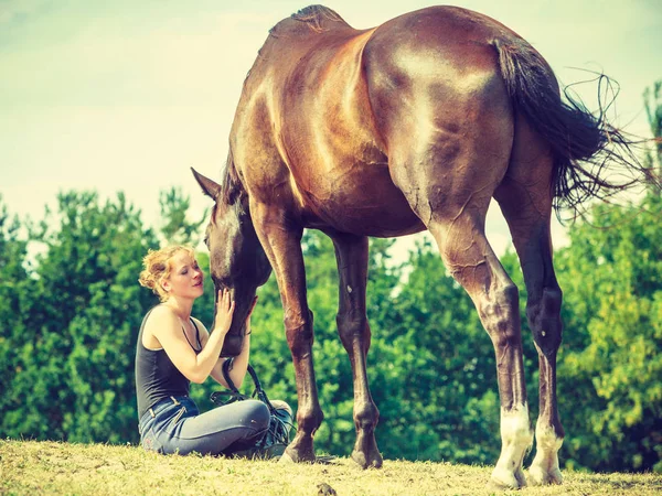 Donna fantino seduta con cavallo sul prato — Foto Stock
