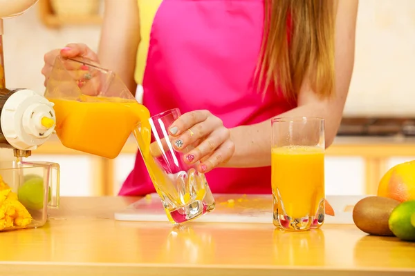 Woman pouring orange juice drink in glass — Stock Photo, Image
