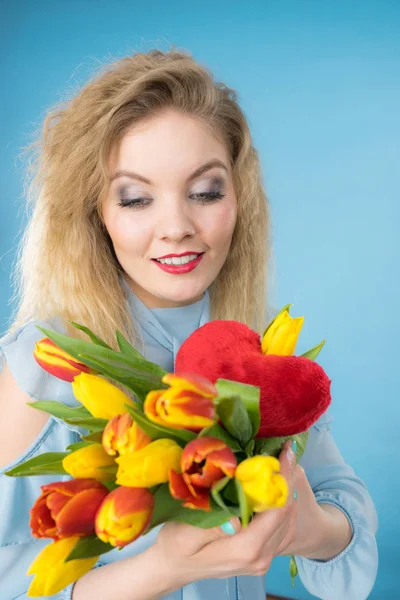 Mujer sostiene tulipanes y corazón rojo — Foto de Stock