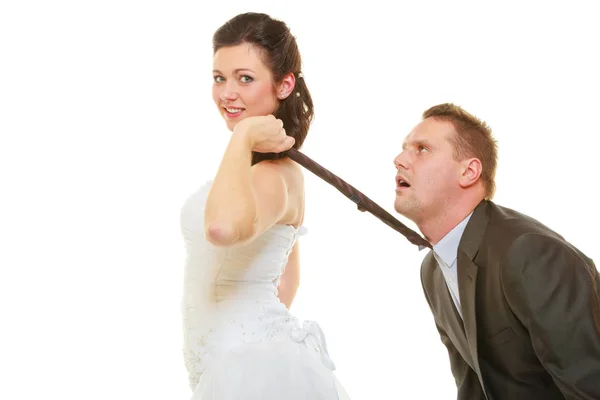 Dominant bride wearing wedding dress pulling groom tie — Stock Photo, Image