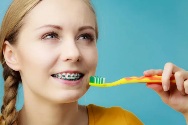Femme avec des appareils dentaires à l'aide d'une brosse — Photo