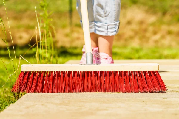 Donna che usa scopa per pulire patio cortile — Foto Stock