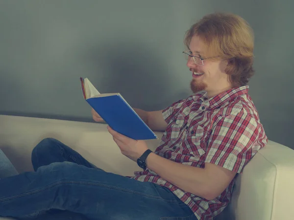 Homme relaxant sur canapé livre de lecture — Photo