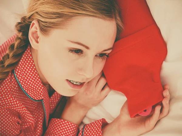 Sıcak kırmızı sıcak su şişesi ile uyuyan kadın — Stok fotoğraf