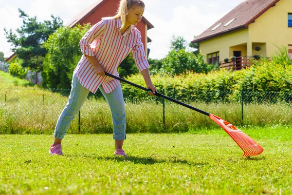 Donna che usa rastrello per pulire il giardino — Foto Stock