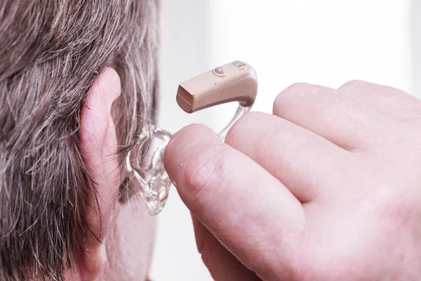 Closeup senior woman using hearing aid — Stock Photo, Image