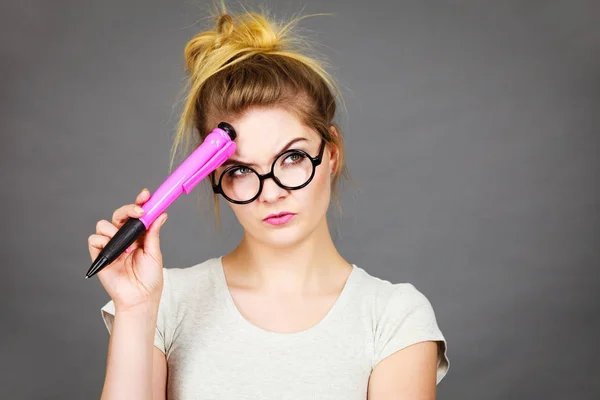 Mujer sosteniendo un gran lápiz de gran tamaño pensando en algo — Foto de Stock